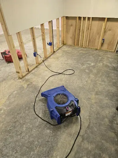 Air mover drying a room with the wall drywall removed down to the studs