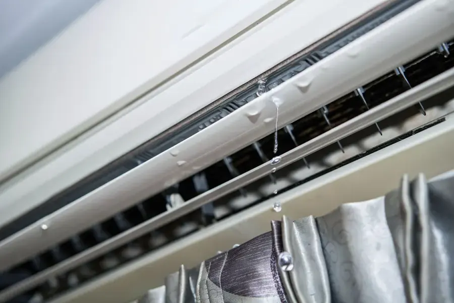 Condensate water dripping from the vents of a wall-mounted air conditioner