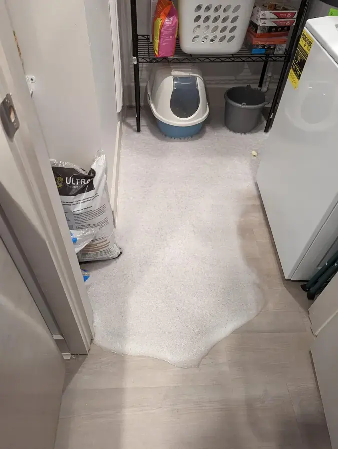 Water spreading across a laundry room floor from a washer leak