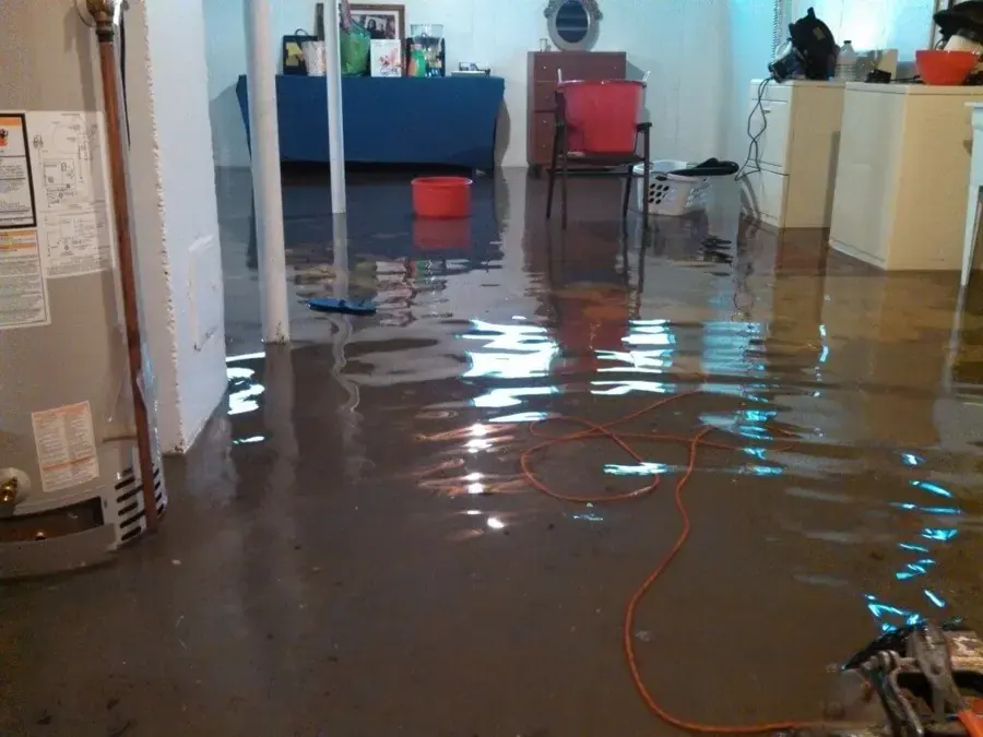 Standing water across a finished basement floor beside the water heater