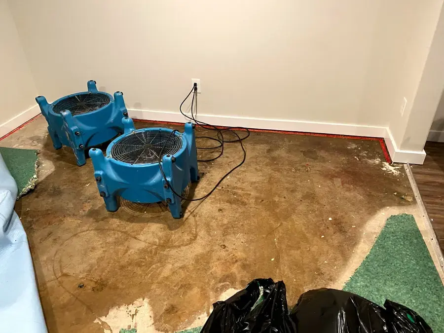 Air movers drying a water-stained floor in a room after a leak